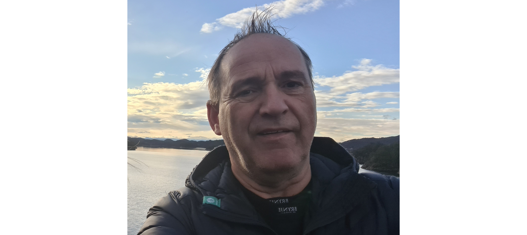 Smilende person i redningsvest i en robåt på fjorden.